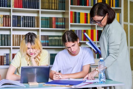 Girls teenage students studying in library with female teacher mentor. High school, education, adolescent, back to school, back to college concept