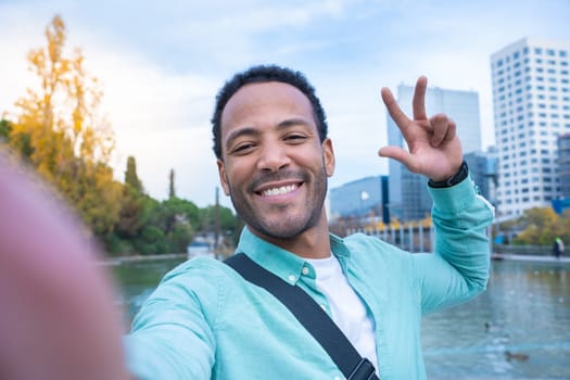 Young African American man taking a selfie looking at camera smiling - Point of view - Tourist traveling student around the world.