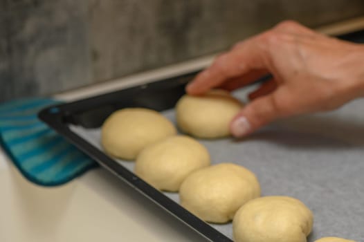 woman placing buns on a baking sheet 3