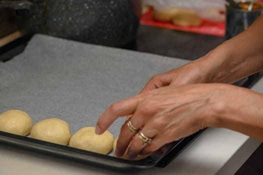 woman placing buns on a baking sheet 4