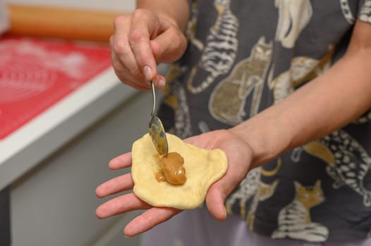 woman putting filling on buns in kitchen