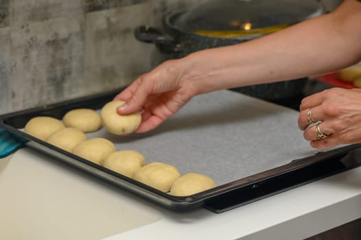 woman placing buns on a baking sheet 6