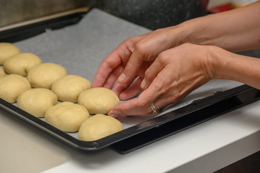 woman placing buns on a baking sheet 12