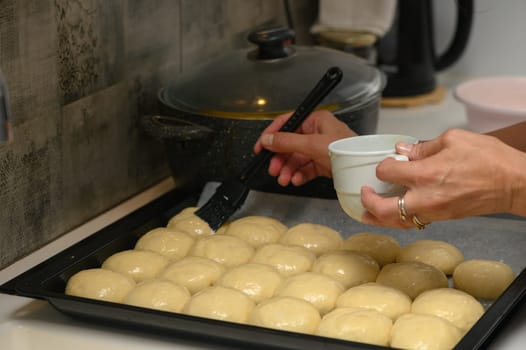 woman greases buns in the kitchen