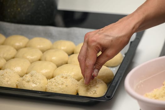 woman sprinkles buns in the kitchen