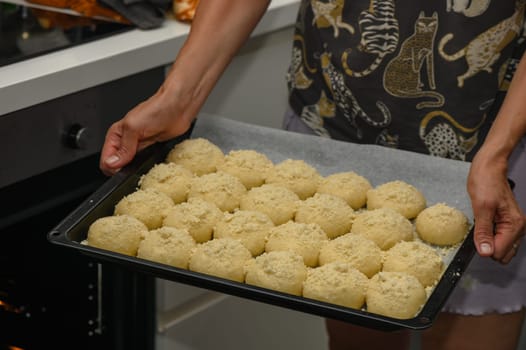 woman puts buns in the oven on a baking sheet 1