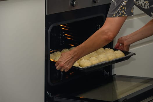 woman puts buns in the oven on a baking sheet 2