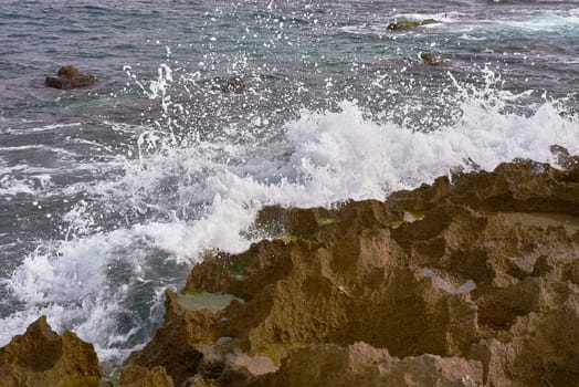 Mediterranean Coastal Rocks with Dynamic Wave Splashes.Seascape of rocky coast with dynamic Mediterranean sea waves, foamy splashes, diagonal rock formations, high shutter speed capture