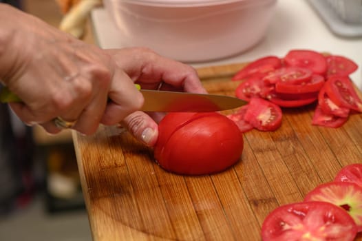 woman cutting tomato on kitchen board 2