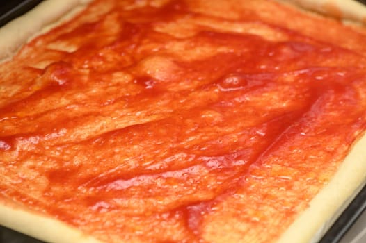 woman smears pizza with tomato ketchup and paste in the kitchen