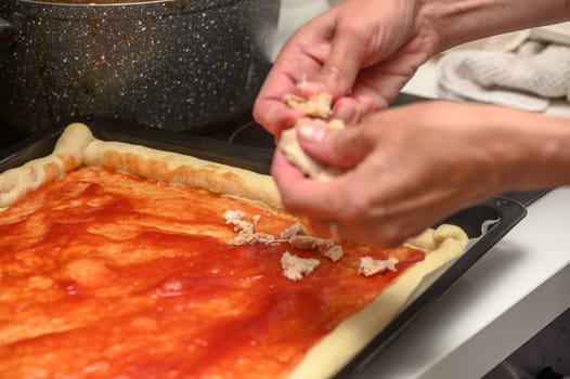 woman putting meat on pizza in the kitchen