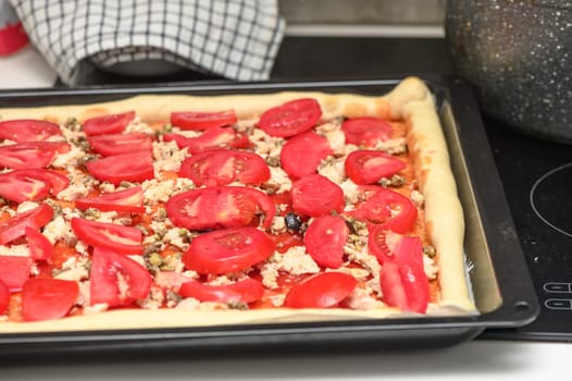 a woman prepares pizza with cheese, tomatoes and chicken ham, a woman lays out tomatoes 6