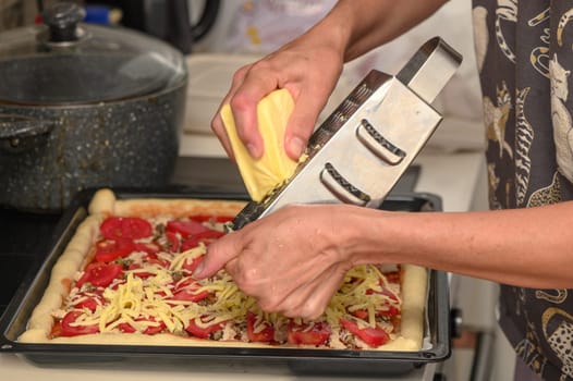 woman prepares pizza with cheese, tomatoes and chicken ham, woman rubs cheese 4