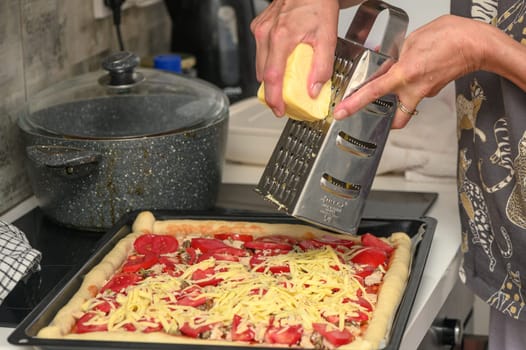 woman prepares pizza with cheese, tomatoes and chicken ham, woman rubs cheese 5