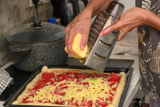 woman prepares pizza with cheese, tomatoes and chicken ham, woman rubs cheese 6