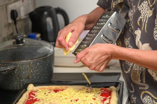 woman prepares pizza with cheese, tomatoes and chicken ham, woman rubs cheese 8