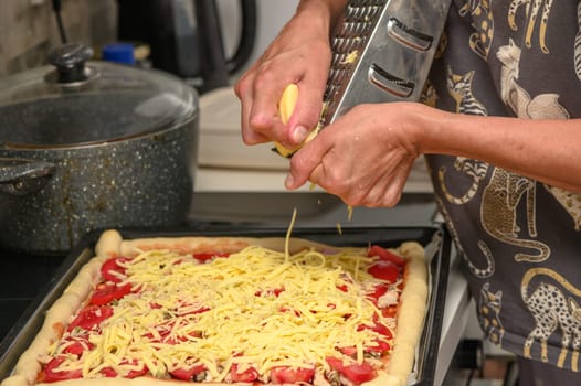 woman prepares pizza with cheese, tomatoes and chicken ham, woman rubs cheese 9