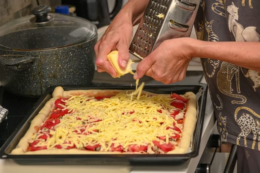 woman prepares pizza with cheese, tomatoes and chicken ham, woman rubs cheese 11