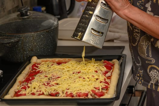 woman prepares pizza with cheese, tomatoes and chicken ham, woman rubs cheese 13