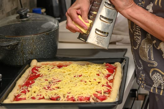 woman prepares pizza with cheese, tomatoes and chicken ham, woman rubs cheese 12