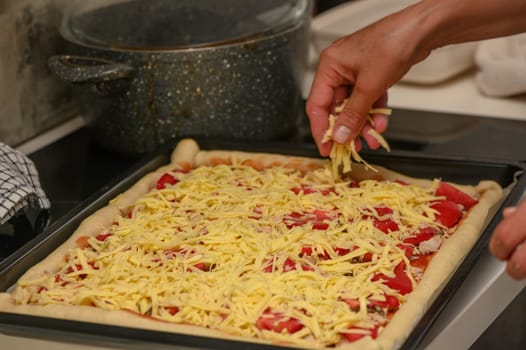 woman prepares pizza with cheese, tomatoes and chicken ham, woman rubs cheese 16