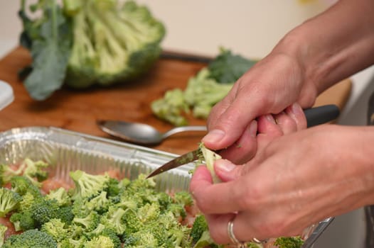 woman cutting broccoli into chicken fillet for baking 11