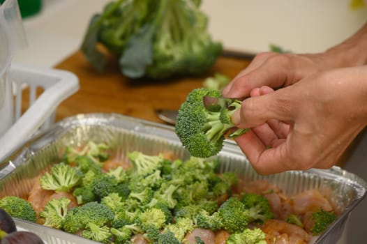 woman cutting broccoli into chicken fillet for baking 9