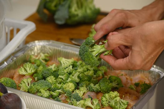 woman cutting broccoli into chicken fillet for baking 8