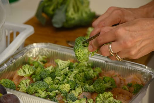 woman cutting broccoli into chicken fillet for baking 7