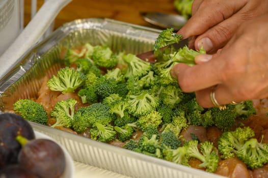 woman cutting broccoli into chicken fillet for baking 4