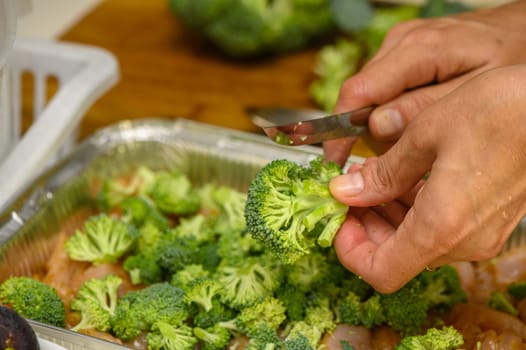 woman cutting broccoli into chicken fillet for baking 5