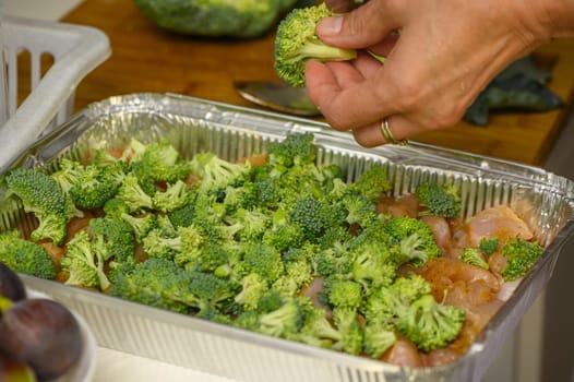 woman cutting broccoli into chicken fillet for baking 2