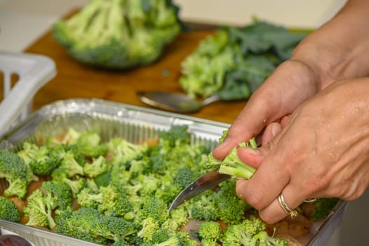 woman cutting broccoli into chicken fillet for baking 3