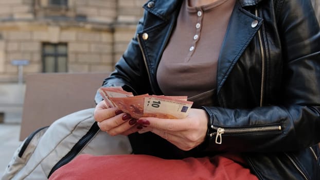 Attractive Woman Counts Euro Cash On City Street Bench