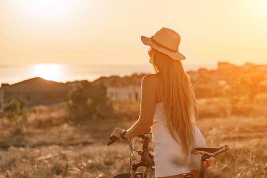 Woman travel bike. Happy woman cyclist sitting on her bike, enjoying the beautiful mountain and sea landscape, signifying the idea of an adventurous bike ride