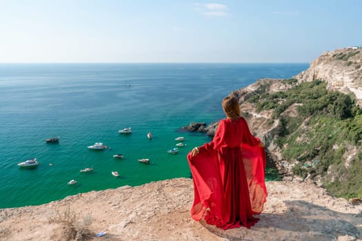 Red Dress Woman sea Cliff. A beautiful woman in a red dress and white swimsuit poses on a cliff overlooking the sea on a sunny day. Boats and yachts dot the background