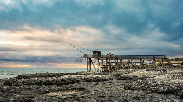 Traditional fisherman hut on stilts with carrelet fishing net. Typical wooden houses for fishing at beach