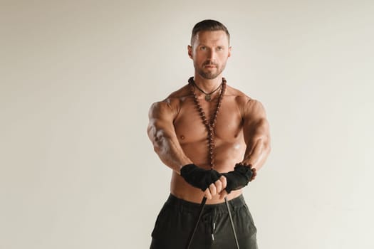 A man with a naked torso is engaged in strength fitness using a rubber loop indoors.