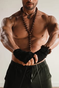 A man with a naked torso is engaged in strength fitness using a rubber loop indoors.