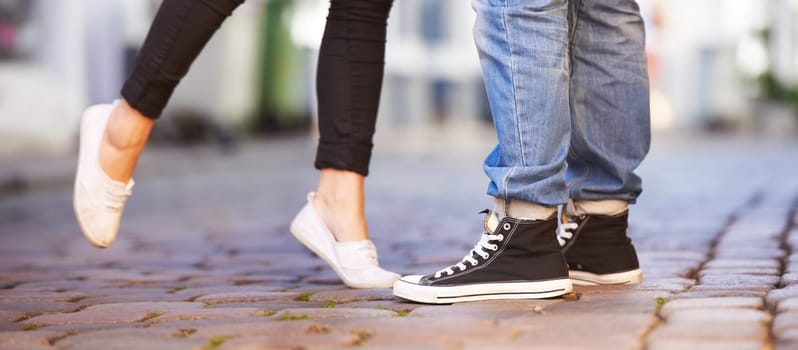 Love, city and shoes of couple on road for date, cute relationship and bonding outdoors on weekend. Dating, romance and closeup of feet of man and woman for flirting, shy and romantic adventure.