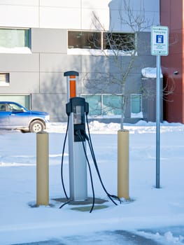 EV charging station on winter season with gas truck parked nearby on an office building background
