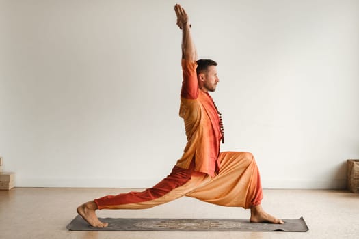 a man in an orange suit does yoga in a fitness room. The concept of health.