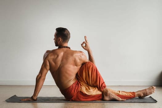 a man with a naked torso does yoga indoors. Fitness Trainer.