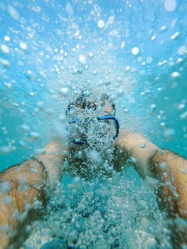 Swimmer in a mask swims in bubbles underwater. High quality photo