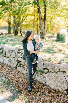 Mom looks at a little girl in her arms walking in the park. High quality photo