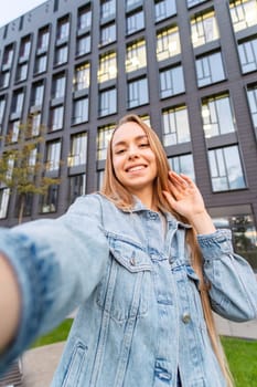 Young beautiful woman with long hair taking a selfie in the street