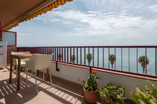 Cozy terrace with small table and houseplants on sea coast in Vilassar de Mar. Interior of tourist apartment at popular Catalonia resort