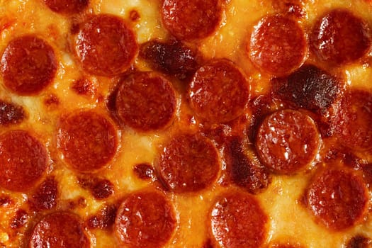Close-up of the surface of pepperoni pizza with sausages and mozzarella.