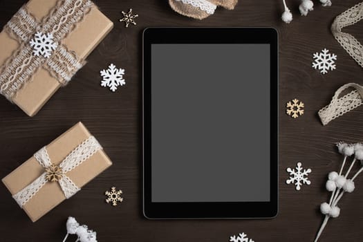 Tablet with a blank screen surrounded by Christmas decorations and gifts, mocap for advertising.