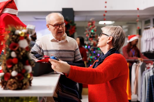 Customers checking accessories in box before buying christmas dinner suit from clothing store on sale. Man and woman looking to buy ties from clearance section during holiday season.